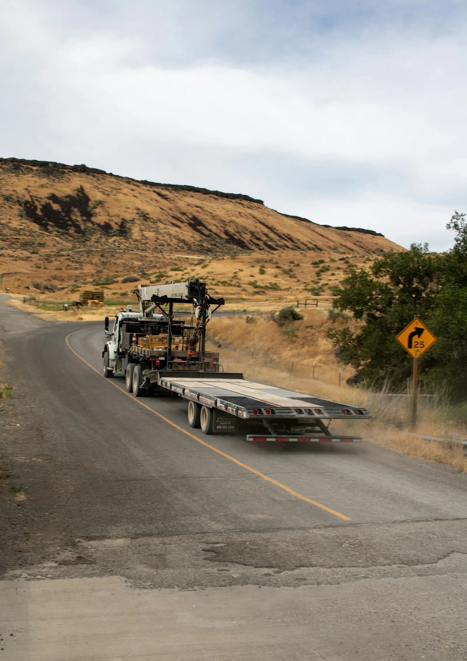 A flatbed truck hauling freight on a rural route